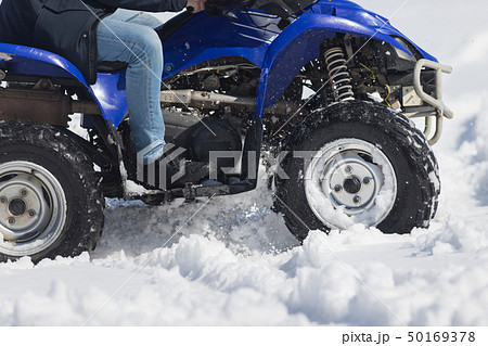A person riding a bright blue snowmobile in the forest 50169378