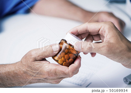 doctor giving a bottle of pills to a senior man 50169934