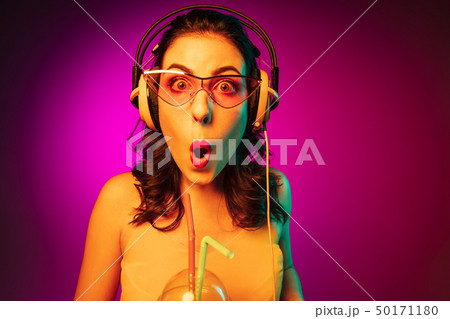 Happy young woman standing and smiling against pink background Happy young woman standing and smiling against pink background 50171180