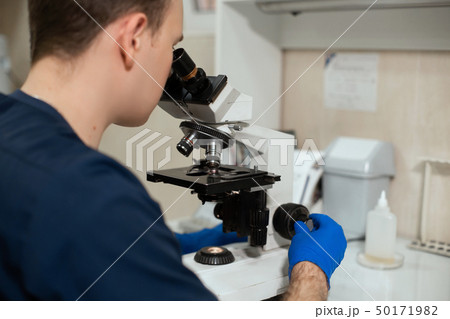 Laboratory assistant looking through microscope. 50171982