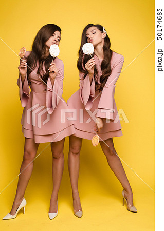 Charming twins closing eyes with lollipops and 50174685