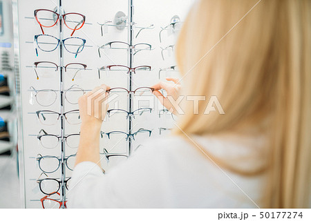 Female optometrist shows glasses in optics store 50177274