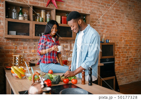 Black man cooking on kitchen, wife drinks coffee 50177328