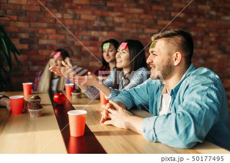 Smiling friends playing sticker notes to forehead 50177495