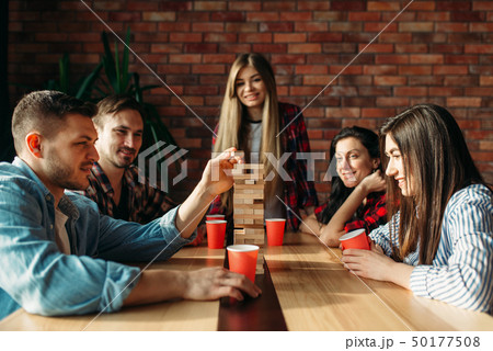 Friends plays table game, selective focus on tower 50177508