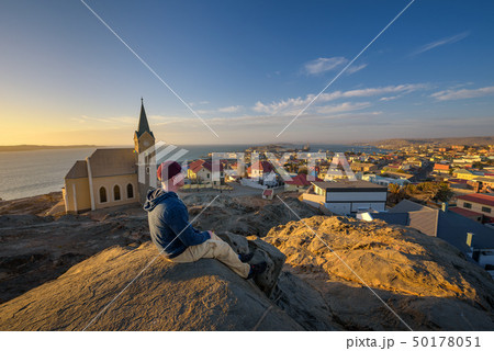 Tourist on top of a hill enjoys the view of Luderitz in Namibia at sunset Tourist on top of a hill enjoys the view of Luderitz in Namibia at sunset 50178051