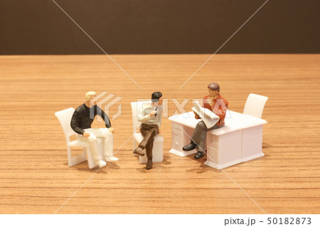 Mini people sit and read the newsapaper 50182873
