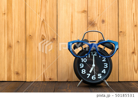 Blue glasses and black vintage alarm clock on the 50185531