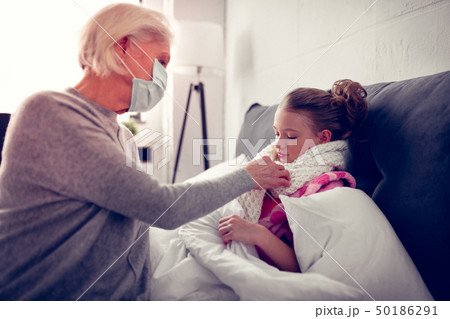 Granny putting warm scarf on her cute girl after catching cold 50186291