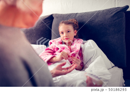Girl staying in bed while feeling sick and looking at granny 50186293