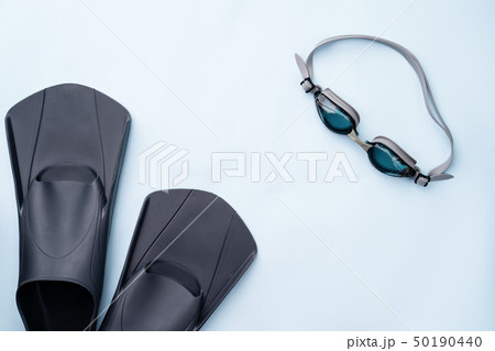 Swimming goggles and flippers on blue background. Swimming goggles and flippers on blue background. 50190440