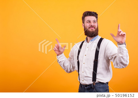Cheerful bearded man smiling and pointing up over yellow background Cheerful bearded man smiling and pointing up over yellow background 50196152