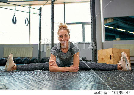 Great progress. Young beautiful woman in sportswear doing stretching in front of window at gym Great progress. Young beautiful woman in sportswear doing stretching in front of window at gym 50199248