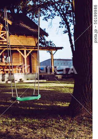 Empty swing in forests garden with wooden house. 50199986