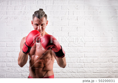 Portrait of handsome boxer man standing on the bric wall and looking at camera with intense gaze 50200031