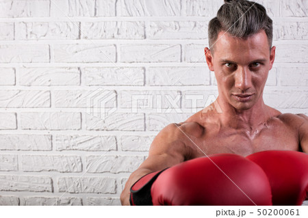 Portrait of handsome boxer man standing on the bric wall and looking at camera with intense gaze Portrait of handsome boxer man standing on the bric wall and looking at camera with intense gaze 50200061