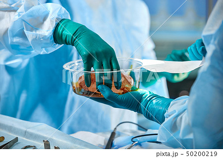 Surgeon performing cosmetic surgery in hospital operating room. Surgeon in mask wearing loupes 50200219