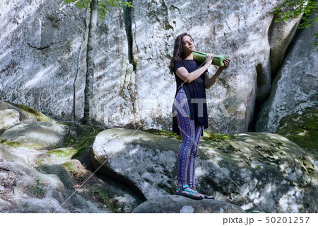 Young attractive girl in the mountains is holding a yoga mat Young attractive girl in the mountains is holding a yoga mat 50201257
