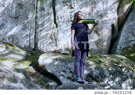 Young attractive girl in the mountains is holding a yoga mat 50201258