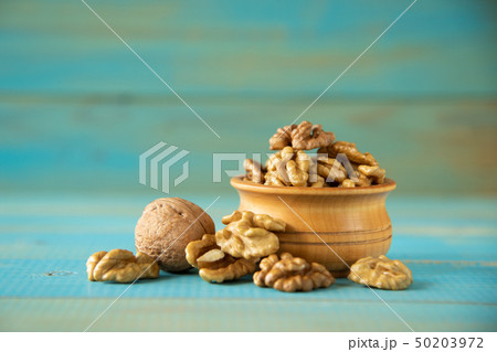 Walnuts on blue rustic table in wooden bowl Walnuts on blue rustic table in wooden bowl 50203972