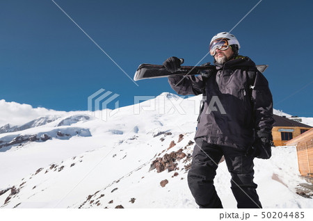Portrait bearded male skier aged against background of snow-capped Caucasus mountains. An adult man Portrait bearded male skier aged against background of snow-capped Caucasus mountains. An adult man 50204485
