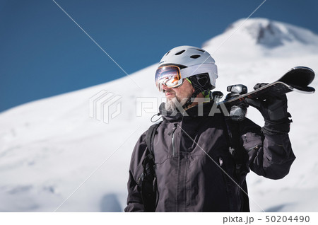 Portrait bearded male skier aged against background of snow-capped Caucasus mountains. An adult man 50204490