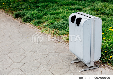 grey metal tresh bin near green grass on alley. 50206656