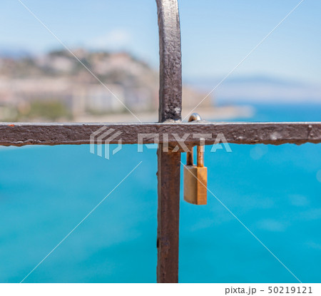 rusty padlock attached to a balustrade by the sea, 50219121