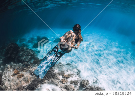 Woman freediver with fins swim in blue sea Woman freediver with fins swim in blue sea 50219524