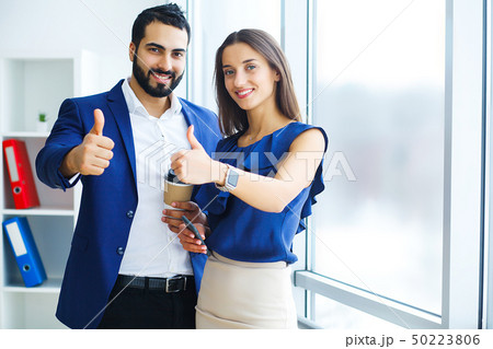 Pretty mixed race woman and her bearded colleague using laptop in order to discuss joint project in 50223806