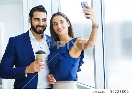 Pretty mixed race woman and her bearded colleague using laptop in order to discuss joint project in 50223809