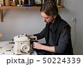 Young male tailor sewing fur on furrier machine 50224339