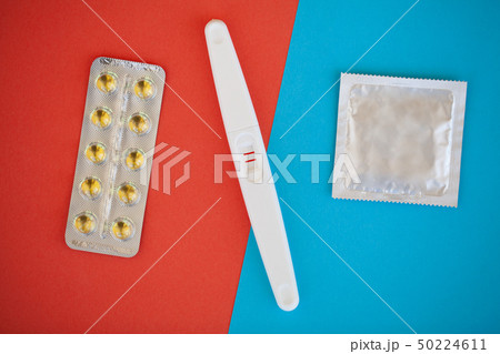 Pregnancy test. The result is positive with two strips and condom with contraceptive on colored 50224611