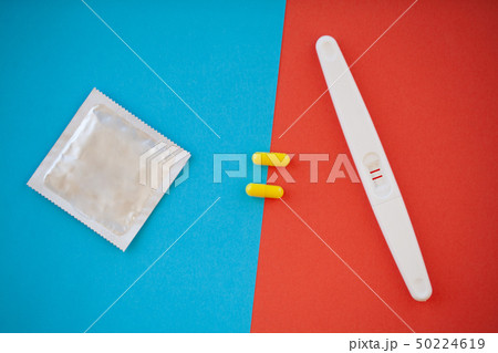 Pregnancy test. The result is positive with two strips and condom with contraceptive on colored 50224619