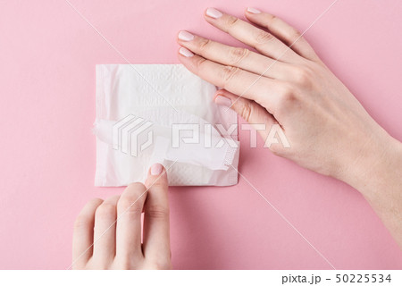 Woman hands hold sanitary pad on a pink background Woman hands hold sanitary pad on a pink background 50225534