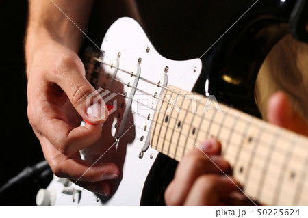 Male hands playing electric guitar with plectrum closeup 50225624