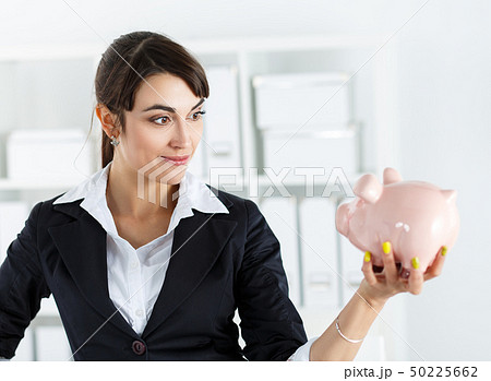 Happy and mysterious beautiful woman holding funny piggybank in hand Happy and mysterious beautiful woman holding funny piggybank in hand 50225662