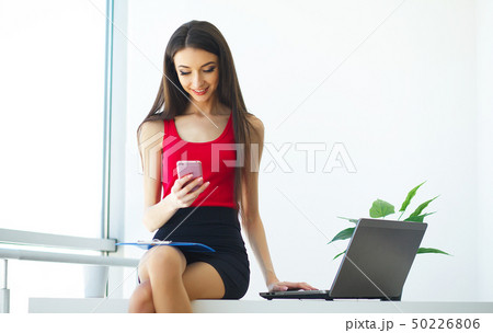 Office. Business Woman Works on the Computer at the Light Modern Office. Dressed in Red Sweater and Office. Business Woman Works on the Computer at the Light Modern Office. Dressed in Red Sweater and 50226806