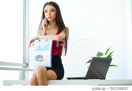 Business. Beautiful Young Woman Works on the Computer. Trims in Hands Phone. Bright Modern Office 50226807