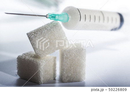 syringe filled with sugar lies on solid sugar cubes on white background 50226809