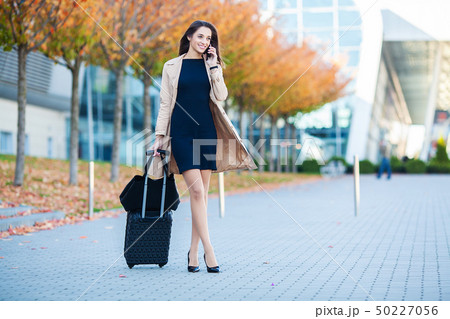 Travel. Business Woman in airport talking on the smartphone while walking with hand luggage in Travel. Business Woman in airport talking on the smartphone while walking with hand luggage in 50227056