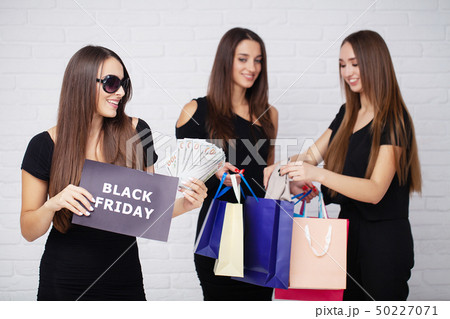 Shopping. Three women holding colored bags on light background in black friday holiday 50227071