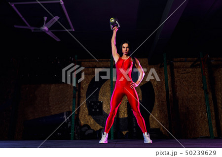 Attractive fit woman athlete performing a kettle-bell swing in gym 50239629