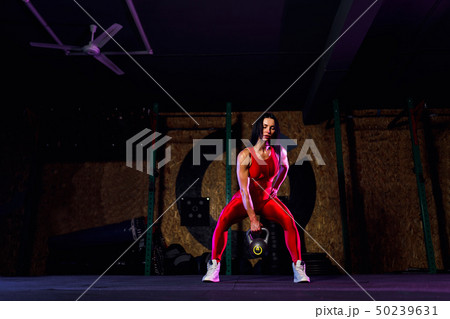 Attractive fit woman athlete performing a kettle-bell swing in gym 50239631