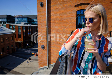 the girl is drinking a cocktail at the rooftop bar the girl is drinking a cocktail at the rooftop bar 50241215