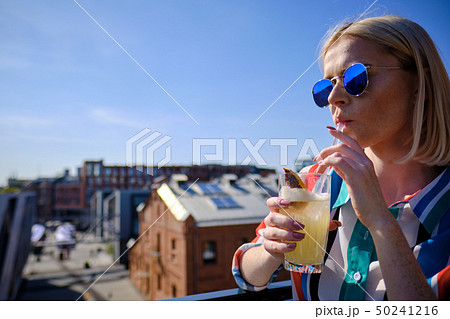 the girl is drinking a cocktail at the rooftop bar the girl is drinking a cocktail at the rooftop bar 50241216