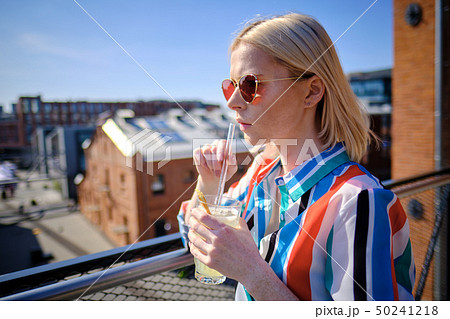the girl is drinking a cocktail at the rooftop bar the girl is drinking a cocktail at the rooftop bar 50241218