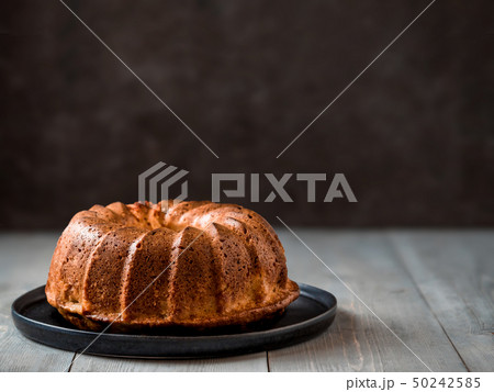 Female hand sprinkling icing sugar on muffin cake 50242585