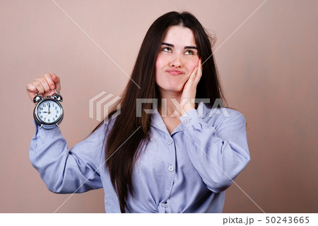 Bored and stressed woman with alarm clock 50243665