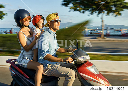 Parents with their child riding motorcycle on sunny city street Parents with their child riding motorcycle on sunny city street 50244005